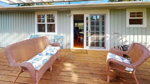A covered outdoor seating area with wicker furniture and a wooden deck.