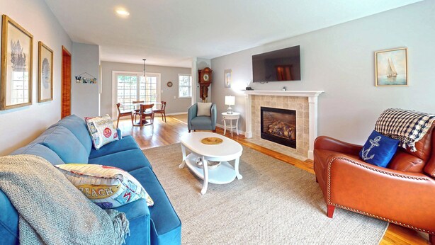 A spacious living room with a blue sofa, a brown leather armchair, a white coffee table, and a fireplace.