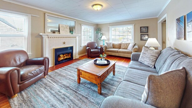 A living room with a fireplace, leather chairs, a sofa, and a coffee table. - Edgewood Escape at Seaside Beach (Seaside)