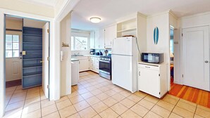 A compact kitchen with white cabinets, a stove, a microwave, and a refrigerator. - Edgewood Escape at Seaside Beach (Seaside)