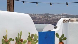 A rooftop terrace with white walls, a blue gate, and potted cacti. - Orasis House – Aegean Cave Retreat with Pool (Akrotiri)