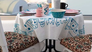 A table with a tablecloth, a pink cup, a blue bowl, and a black mug. - Orasis House – Santorini Retreat w/ Pool & Views (Akrotiri)