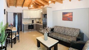 A modern living room with a sofa, a dining table with chairs, and a kitchen area with cabinets and appliances.