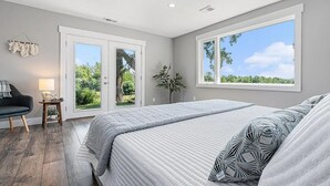 Un dormitorio con una cama grande, un escritorio, una silla y una ventana con vistas a zonas verdes.