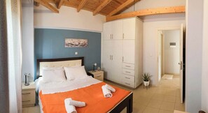 Une chambre à coucher avec un lit, une table de chevet, une armoire et une plante en pot.