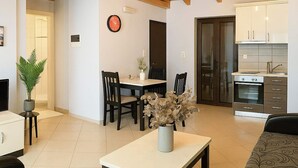 A spacious living area with a dining table, chairs, a coffee table with a vase, a sofa, and a kitchen with cabinets and appliances. - Villa Orestis - Stoupa Seaview Getaway (Stoupa)