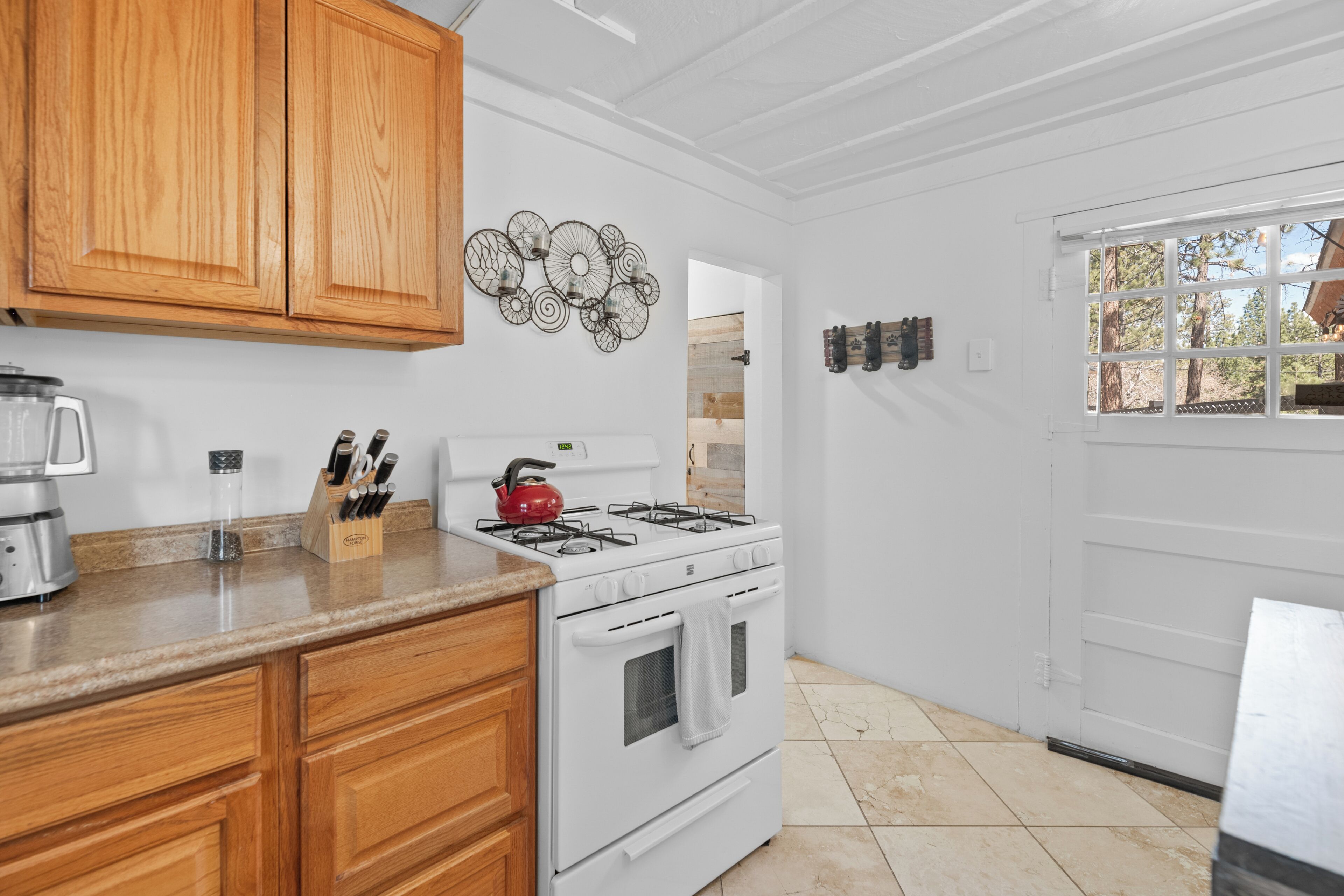 Una cocina con armarios de madera, estufa a gas, cafetera y un adorno en la pared.