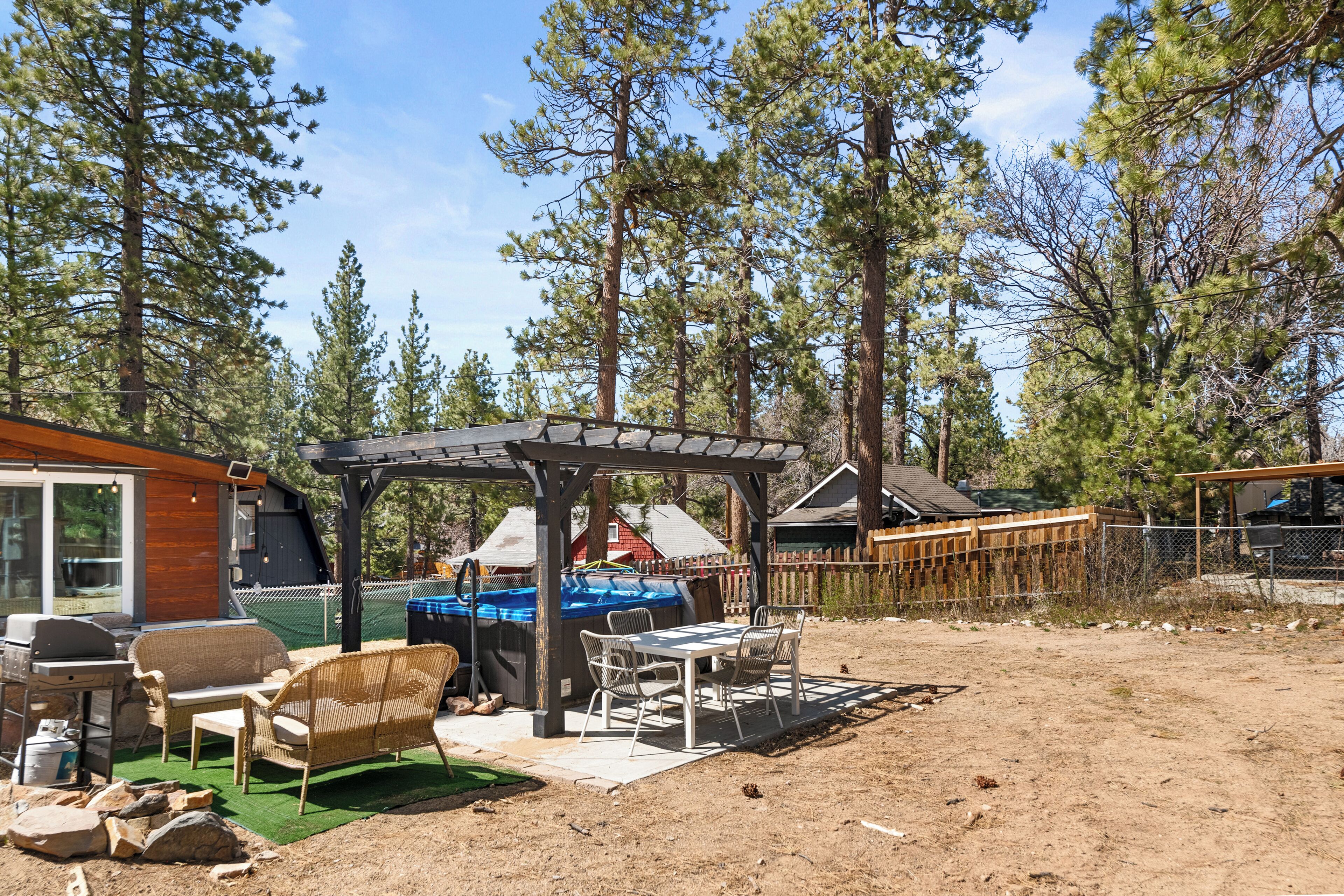 A covered outdoor seating area with a grill, chairs, and a table.