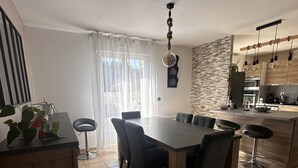 A modern kitchen with a central island, a dining area with a large table and chairs, and a kitchen island with bar stools.