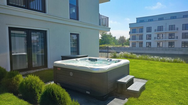 A modern building with a hot tub in the yard.