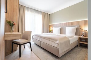 A modern hotel room with a large bed, a desk, and a chair.
