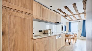Una cocina moderna con armarios de madera, horno empotrado y comedor con mesa y sillas.