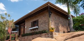 A brick house with a porch, a window, and a potted plant.