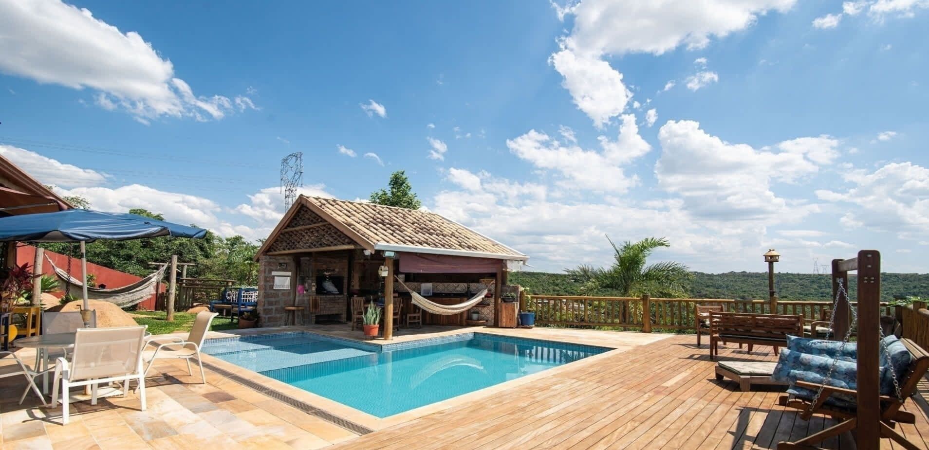 Un pontile in legno con una piscina, un piccolo edificio in pietra con tetto in tegole e un'amaca.