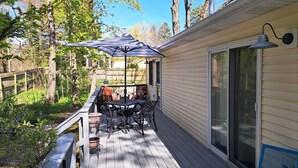A covered outdoor patio with a table and chairs, a wooden deck, and a view of a house. - Steps to McKinley Beach walk to all in Union Pier Fire Pit (Union Pier)