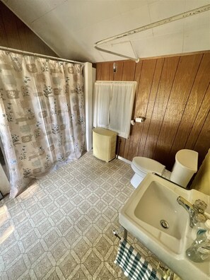 A bathroom with a toilet, sink, and shower curtain. - Harmon's Beach Limit 5 1 Bedroom Villa (Standish)