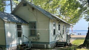A two-story house with a porch, located near a body of water.