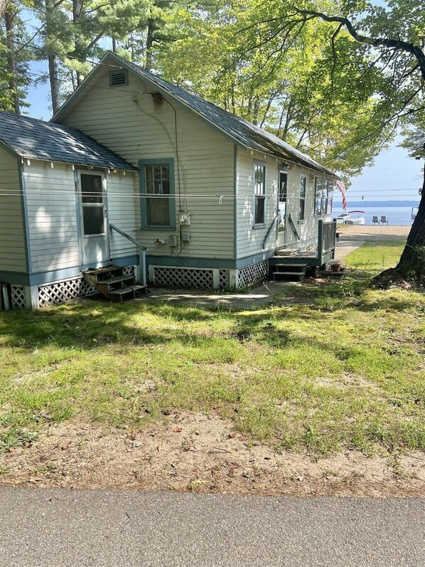 A two-story house with a porch, located near a body of water. - Harmon's Beach Limit 5 1 Bedroom Villa (Standish)