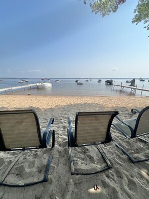 A beach with rows of empty beach chairs facing the sea, a sandy shore, and several boats anchored in the water. - Harmon's Beach Limit 5 1 Bedroom Villa (Standish)
