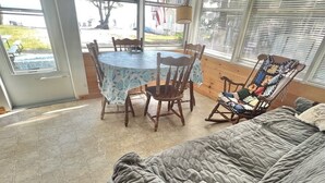 A cozy room with a large bed, a dining table with chairs, and a rocking chair.