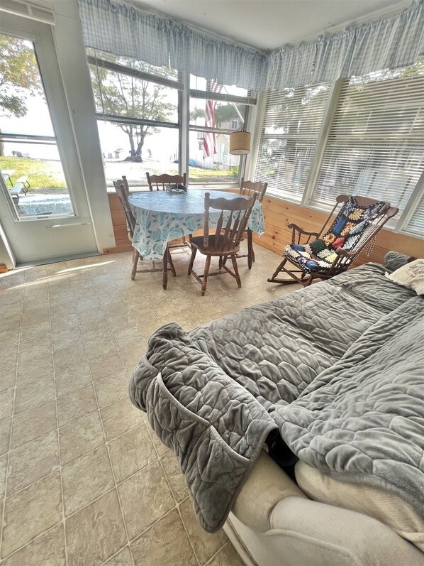 A cozy room with a large bed, a dining table with chairs, and a rocking chair.