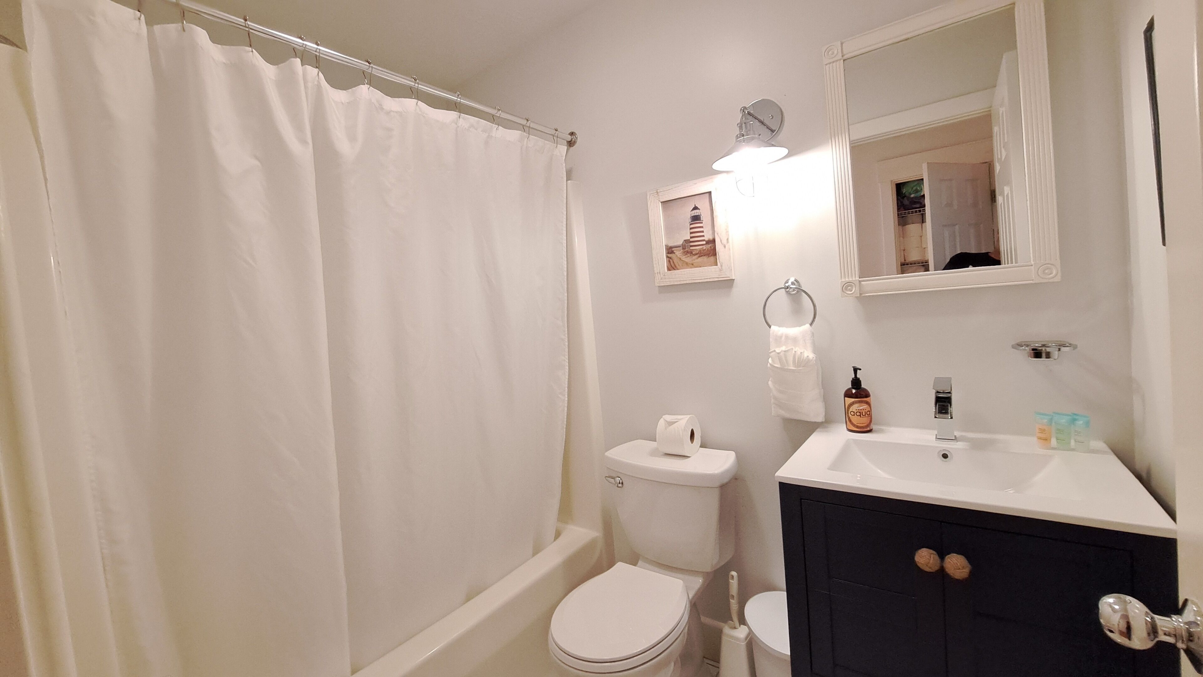 A bathroom with a bathtub, toilet, sink, and a shower curtain.