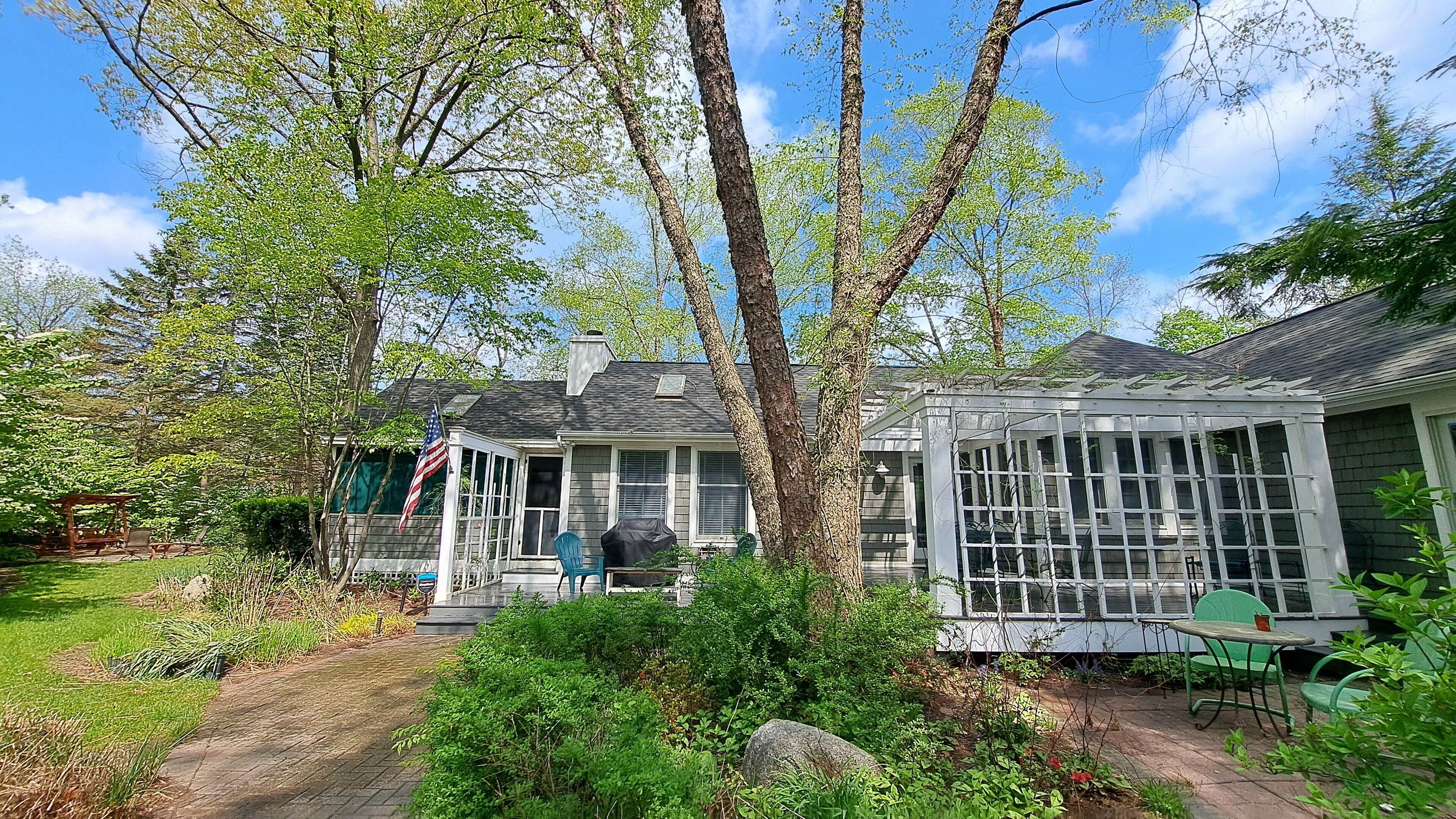 A house with a covered porch, a conservatory, and a flag.