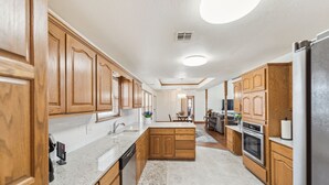 Una cocina con armarios de madera, encimera de granito, horno empotrado y una isla central.