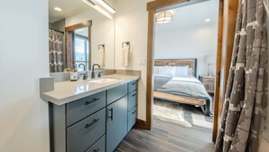A modern bathroom with a large mirror, dual sinks, and a vanity with drawers. - Downtown Penthouse Condo – For 6! (Columbia Falls)