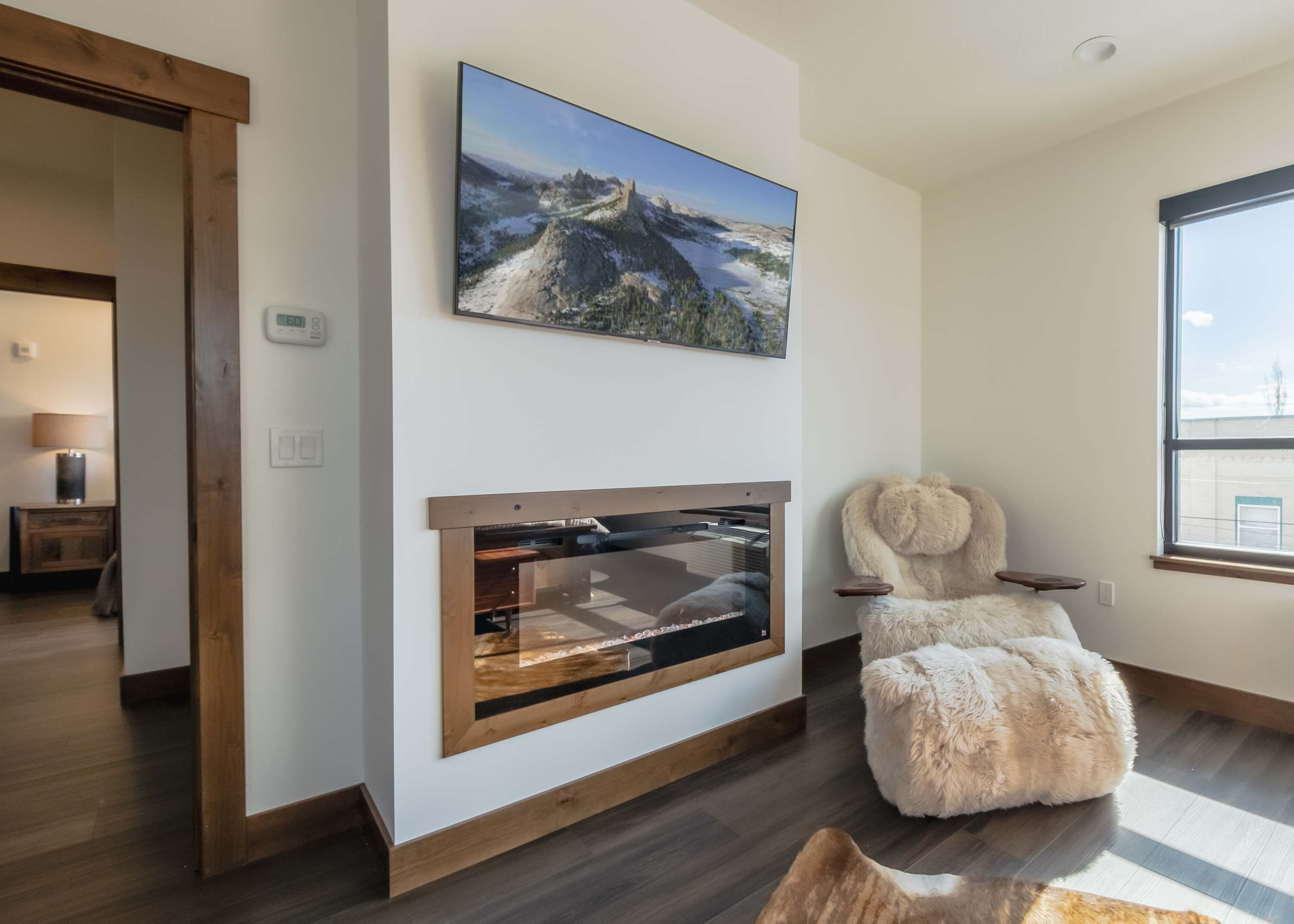 Una sala de estar moderna con chimenea, un ventanal grande y un sillón mullido.