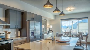 A modern kitchen with grey cabinets, stainless steel appliances, and pendant lighting. - Downtown Penthouse Condo – For 6! (Columbia Falls)
