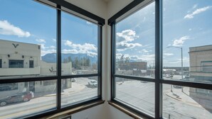Ein Eckzimmer mit großen Fenstern mit Blick auf eine Straße und Berge.