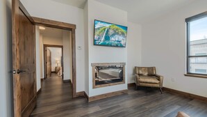 Ein geräumiges Wohnzimmer mit Kamin, einem großen Fenster und einer gemütlichen Sitzecke.