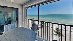 Un balcon avec vue sur l’océan, une table, des chaises et un ventilateur de plafond.