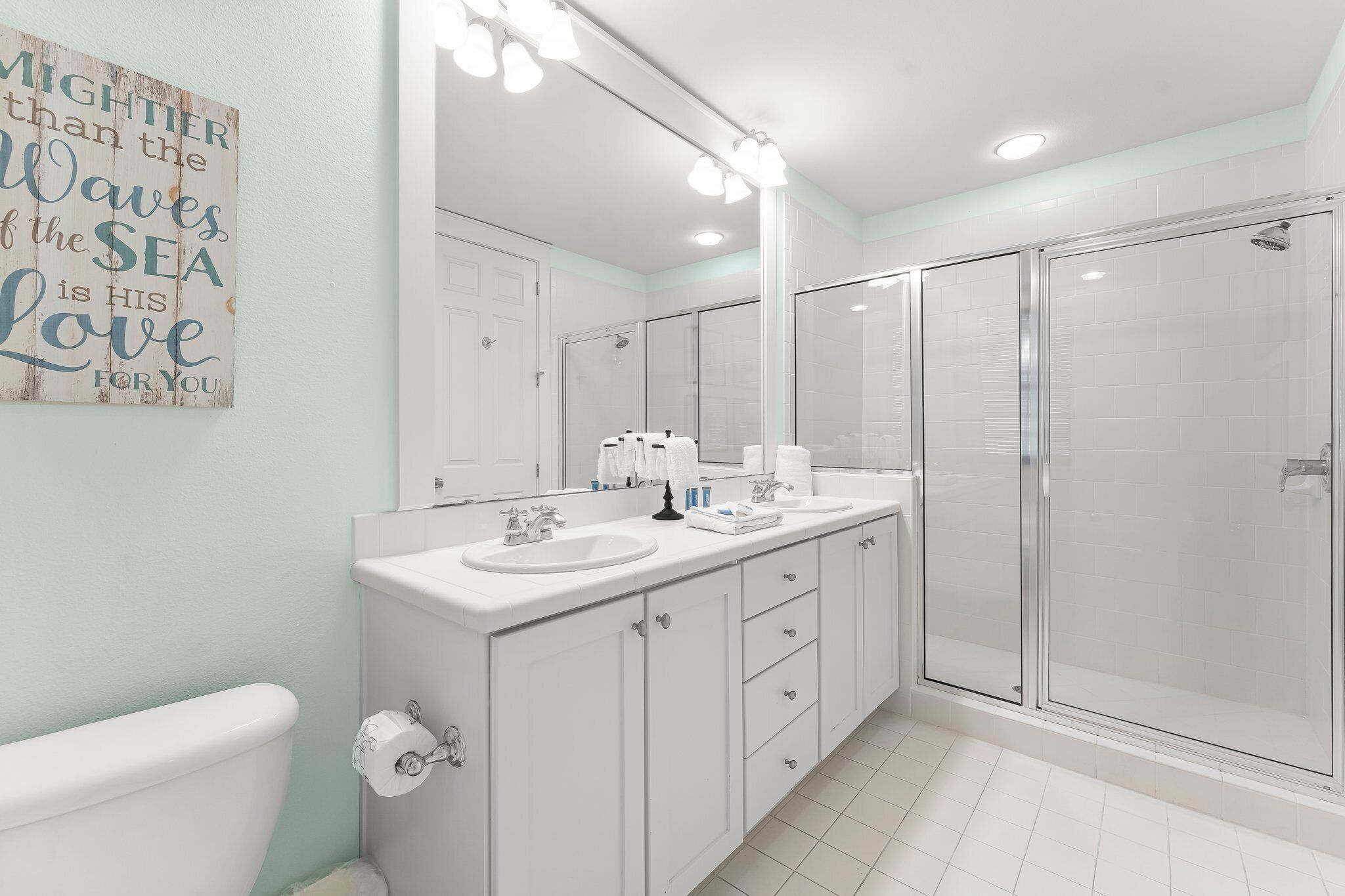 A modern bathroom with a double sink vanity, a large mirror, and a glass-enclosed shower.