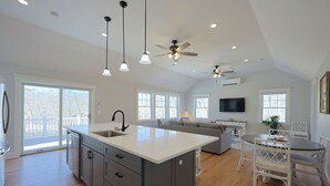 A spacious kitchen with a large island, a dining area with white furniture, and a living room with a TV and seating. - Life of Reilly - Private & Serene Rockport Escape (Rockport)
