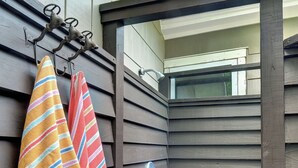Un mur extérieur en bois sur lequel est fixé un porte-serviettes en métal, où sont suspendues des serviettes à rayures.