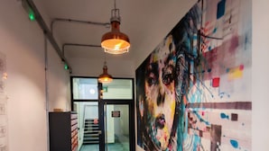 Ein Flur mit Fliesenboden, einem großen abstrakten Gemälde an der Wand und einer Treppe im Hintergrund.