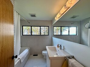 Features a bathtub, sink, and toilet, with a window for natural light and a towel rack.