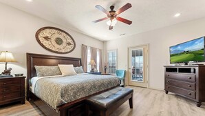 A bedroom with a bed, a ceiling fan, a dresser, a television, and a window with curtains. - The Nest on Birdie Lane - For 8! (Branson West)