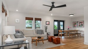 Ein modernes Wohnzimmer mit einer Couch, einem Couchtisch und einem Essbereich mit Tisch und Stühlen.