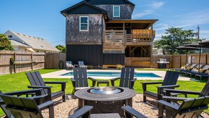 Ein zweistöckiges Haus mit Garten, das einen Pool, Sitzgelegenheiten im Freien und eine Feuerstelle bietet.
