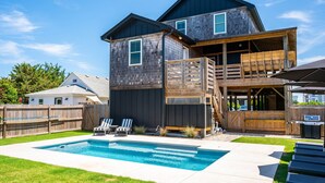 Ein zweistöckiges Haus mit Garten, Pool, Holzterrasse und Grillplatz.