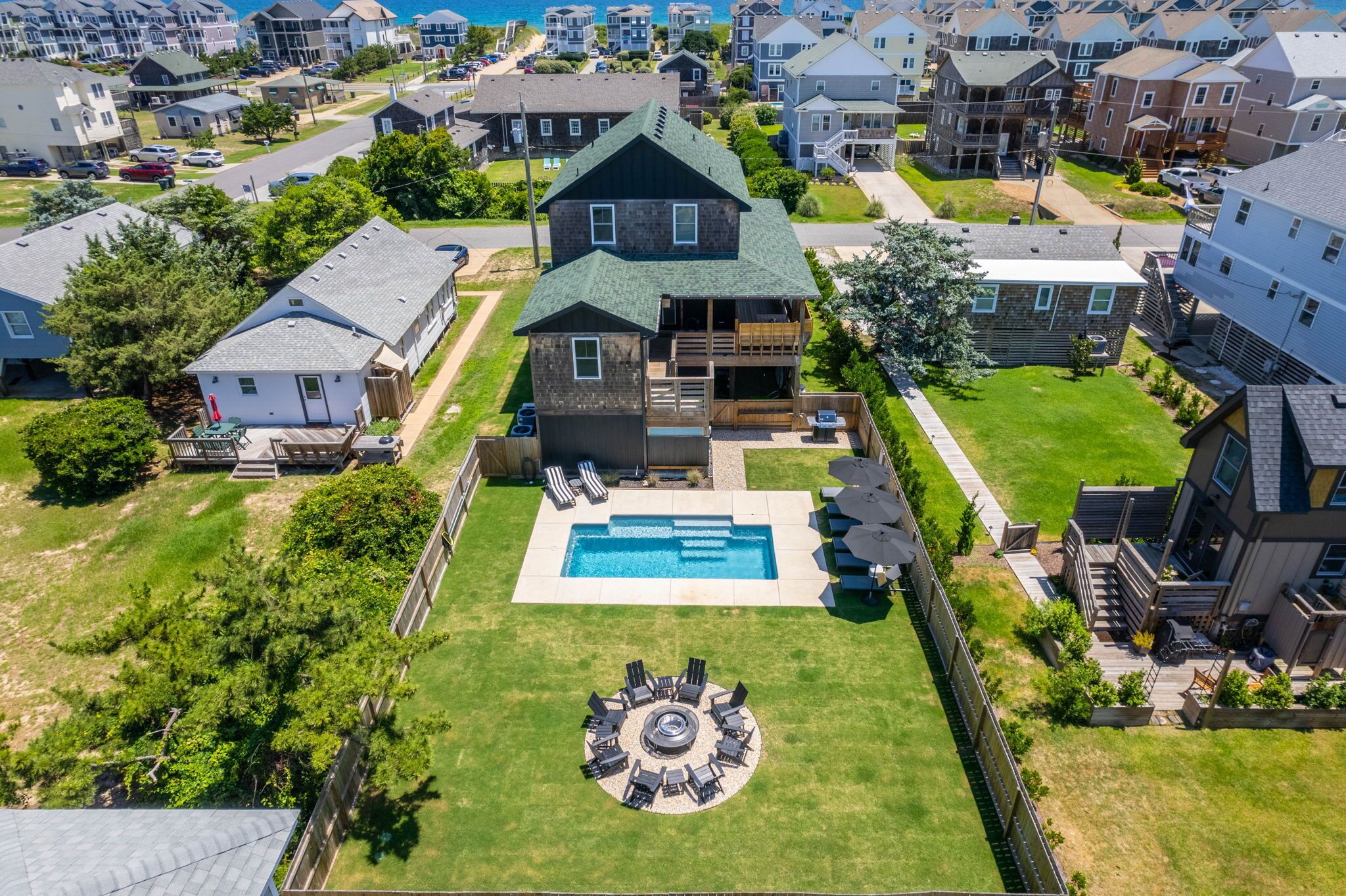 A residential area with a large house featuring a swimming pool, a circular outdoor seating area, and a balcony.