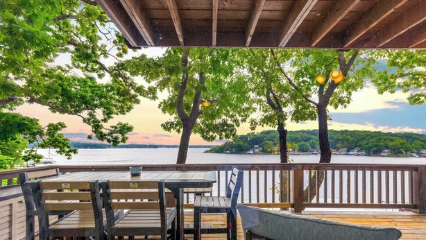 An outdoor deck with wooden furniture and a view of a lake. - Dockside Dream w/ Kayak & Dock (Rocky Mount)