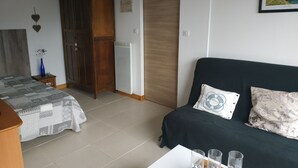 Een slaapkamer met een bed, een dressoir, een kast, een radiator en een lijst met een afbeelding aan de muur.