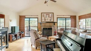 Amplia sala de estar con chimenea, un piano y cómodos asientos.