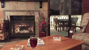 Una sala de estar acogedora con chimenea, un comedor con mampara de vidrio y un sofá cómodo.