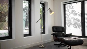 A modern office space with a leather chair, a floor lamp, and large windows.