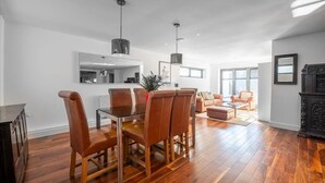 A modern living room with a dining area, hardwood flooring, and contemporary furniture.